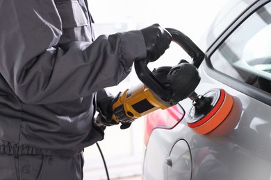 Photo of Man polishing car with orbital polisher indoors, closeup