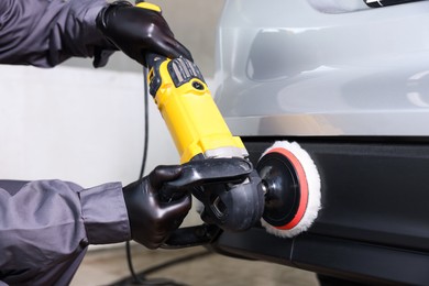 Photo of Man polishing car with orbital polisher indoors, closeup