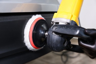 Photo of Man polishing car with orbital polisher indoors, closeup