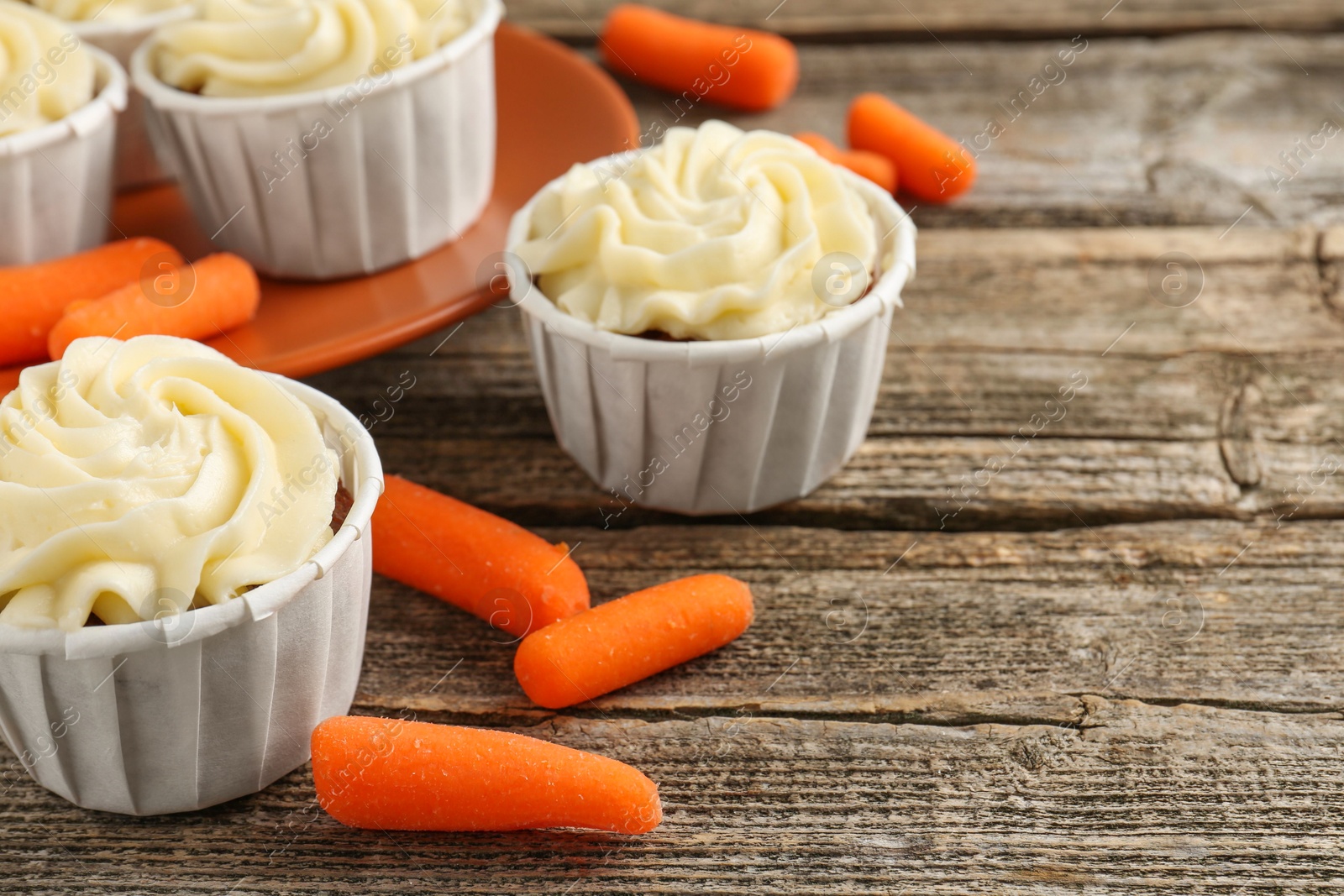 Photo of Tasty carrot muffins and fresh vegetables on wooden table, closeup. Space for text