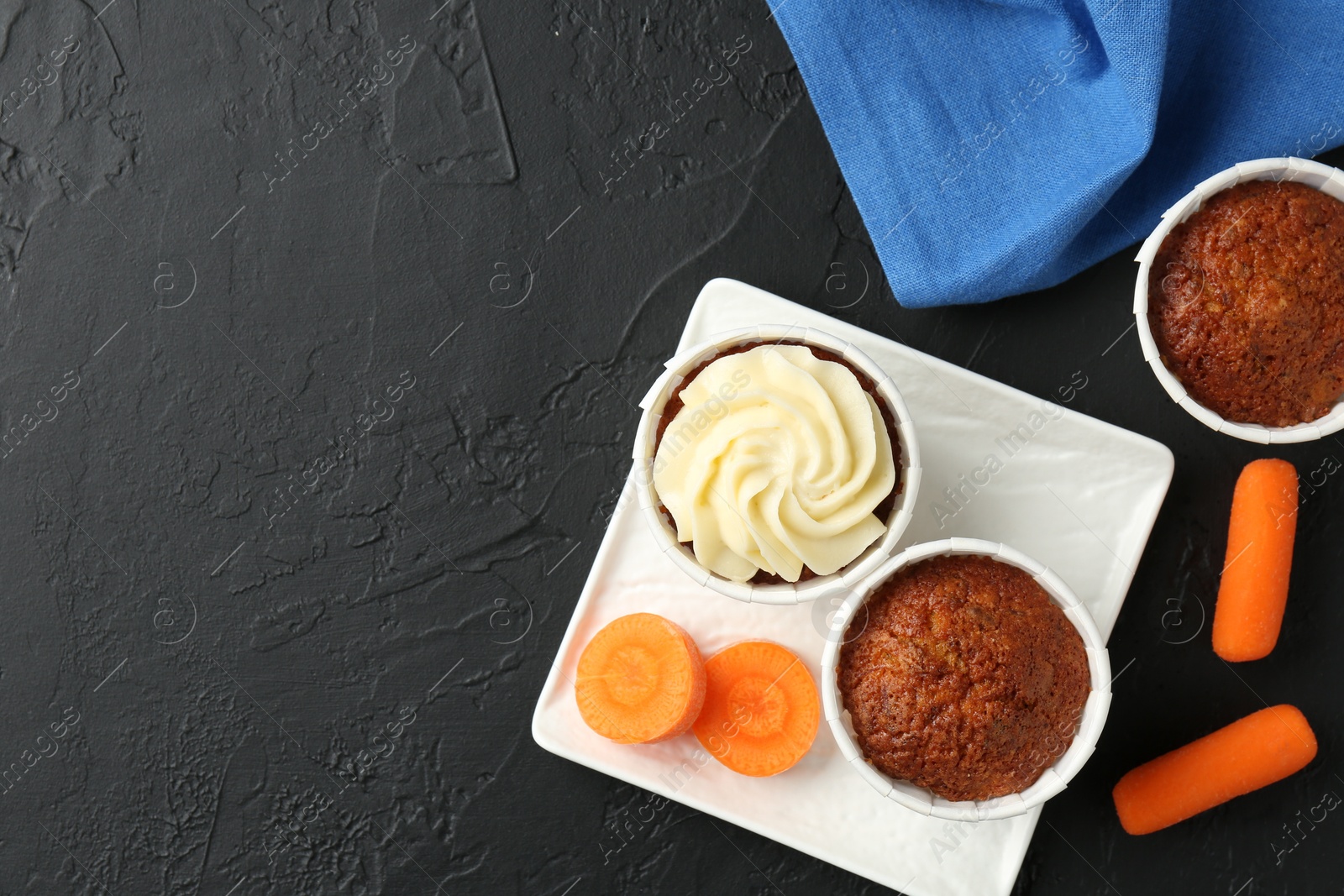 Photo of Tasty carrot muffins with fresh vegetables on grey table, flat lay. Space for text