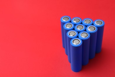 Photo of Many AA cell batteries on red background, closeup. Space for text