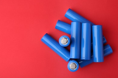 Photo of Many AA cell batteries on red background, top view. Space for text