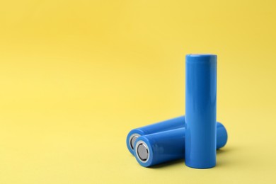 Photo of Three AA cell batteries on yellow background, closeup. Space for text