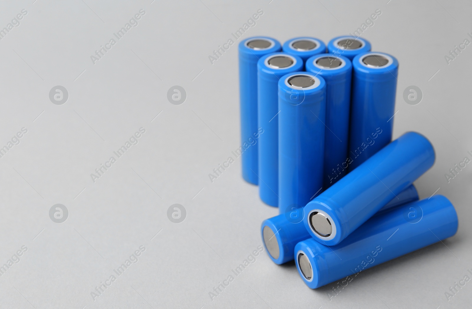 Photo of Many AA cell batteries on light grey background, closeup. Space for text