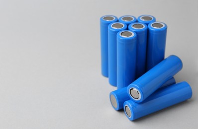 Photo of Many AA cell batteries on light grey background, closeup. Space for text