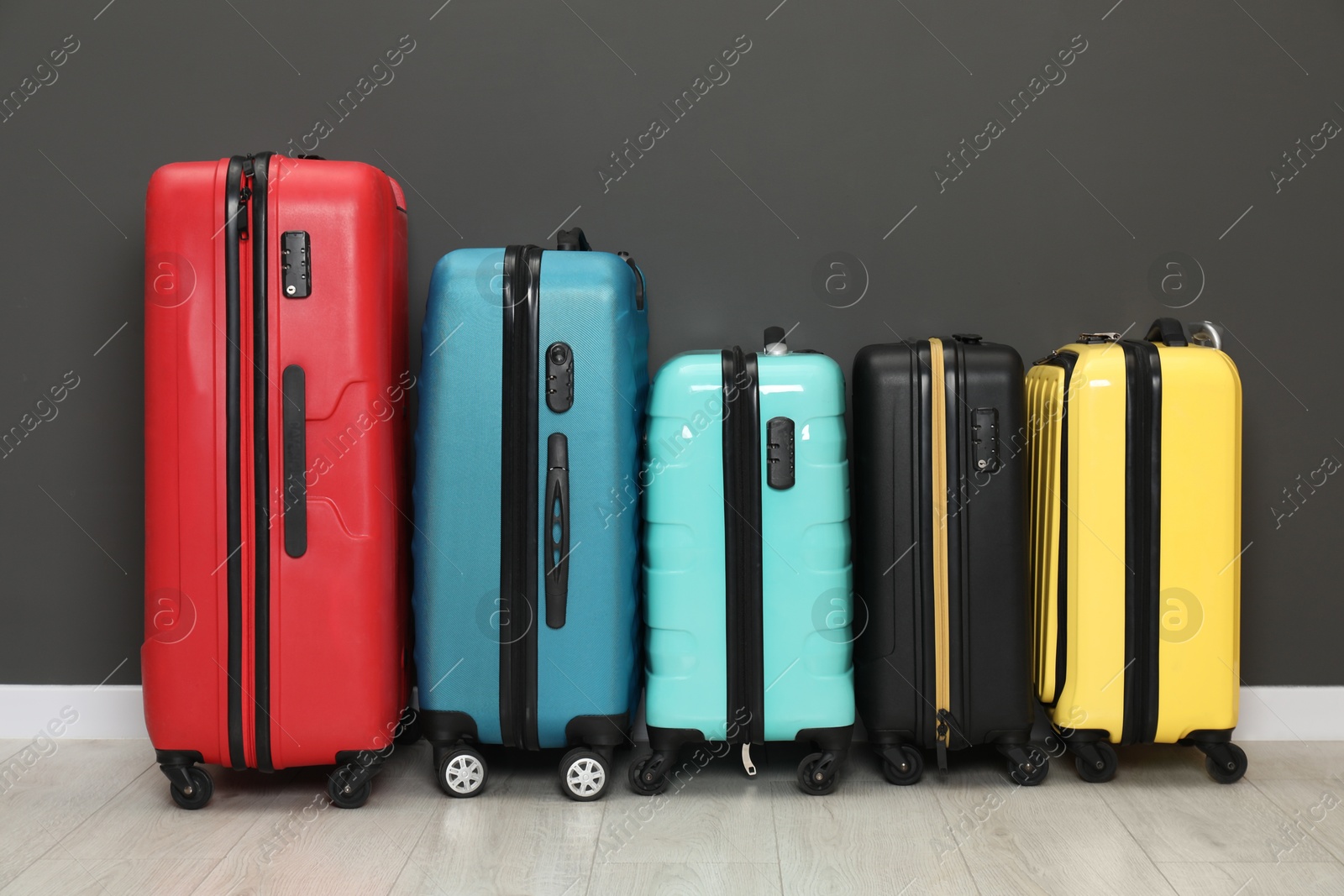 Photo of Colorful suitcases on floor near black wall