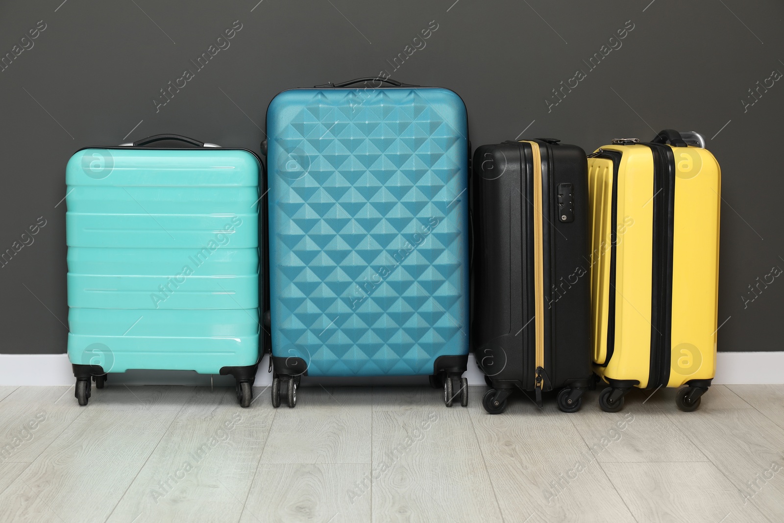 Photo of Colorful suitcases on floor near black wall