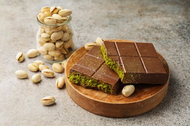 Photo of Pieces of Dubai chocolate bar with pistachios and knafeh on grey table