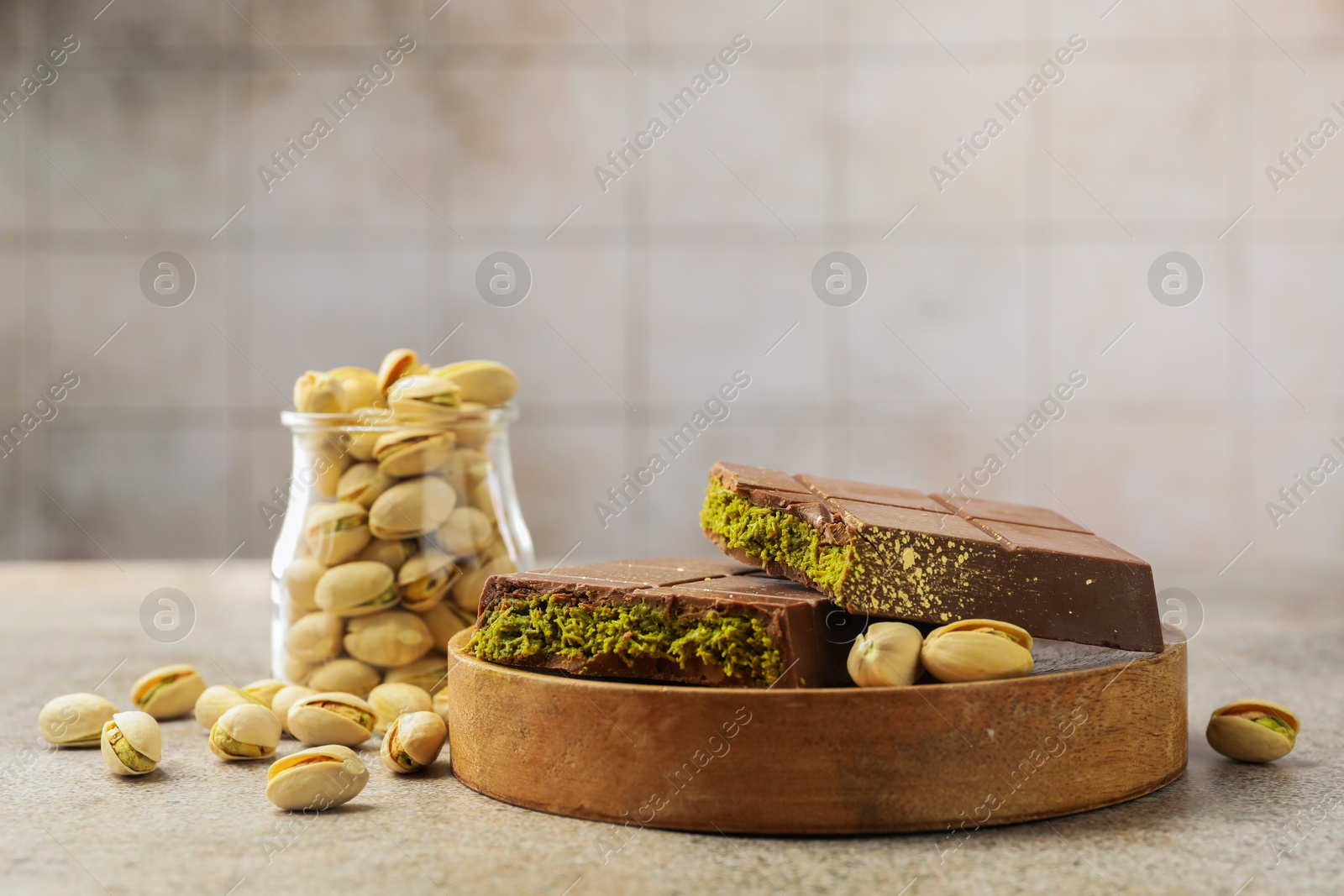 Photo of Pieces of Dubai chocolate bar with pistachios and knafeh on grey table