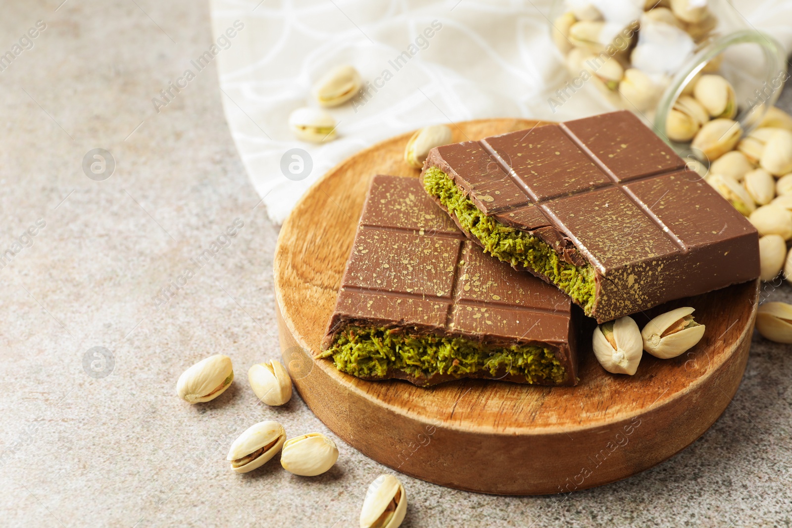 Photo of Pieces of Dubai chocolate bar with pistachios and knafeh on grey table, closeup. Space for text