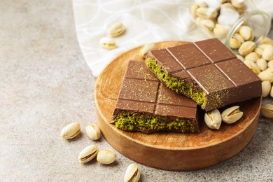 Photo of Pieces of Dubai chocolate bar with pistachios and knafeh on grey table, closeup. Space for text