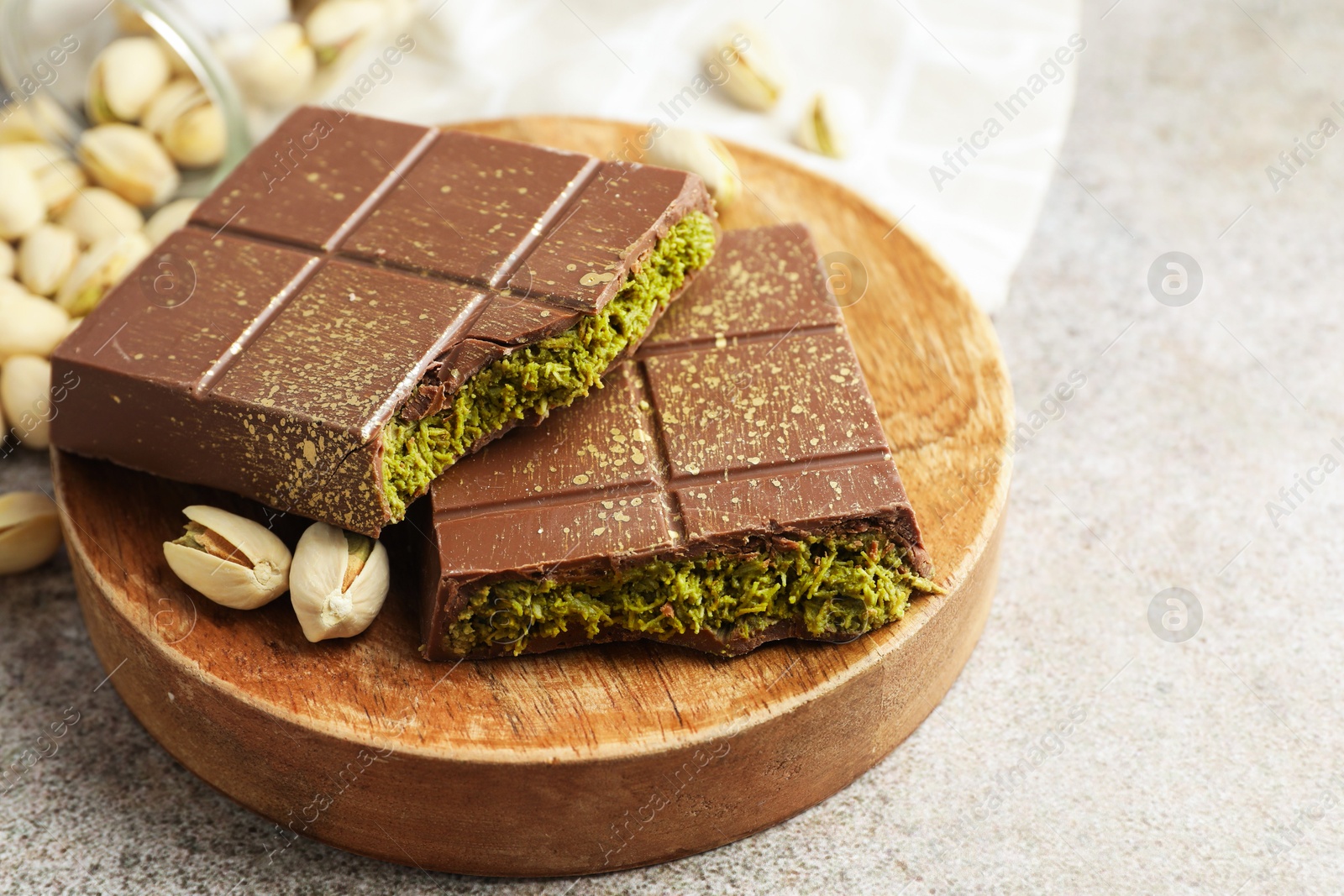 Photo of Pieces of Dubai chocolate bar with pistachios and knafeh on grey table, closeup