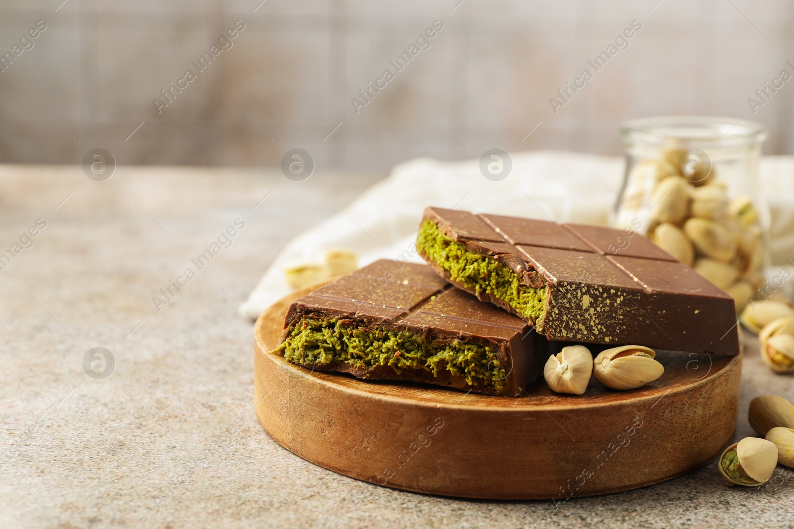 Photo of Pieces of Dubai chocolate bar with pistachios and knafeh on grey table, closeup. Space for text