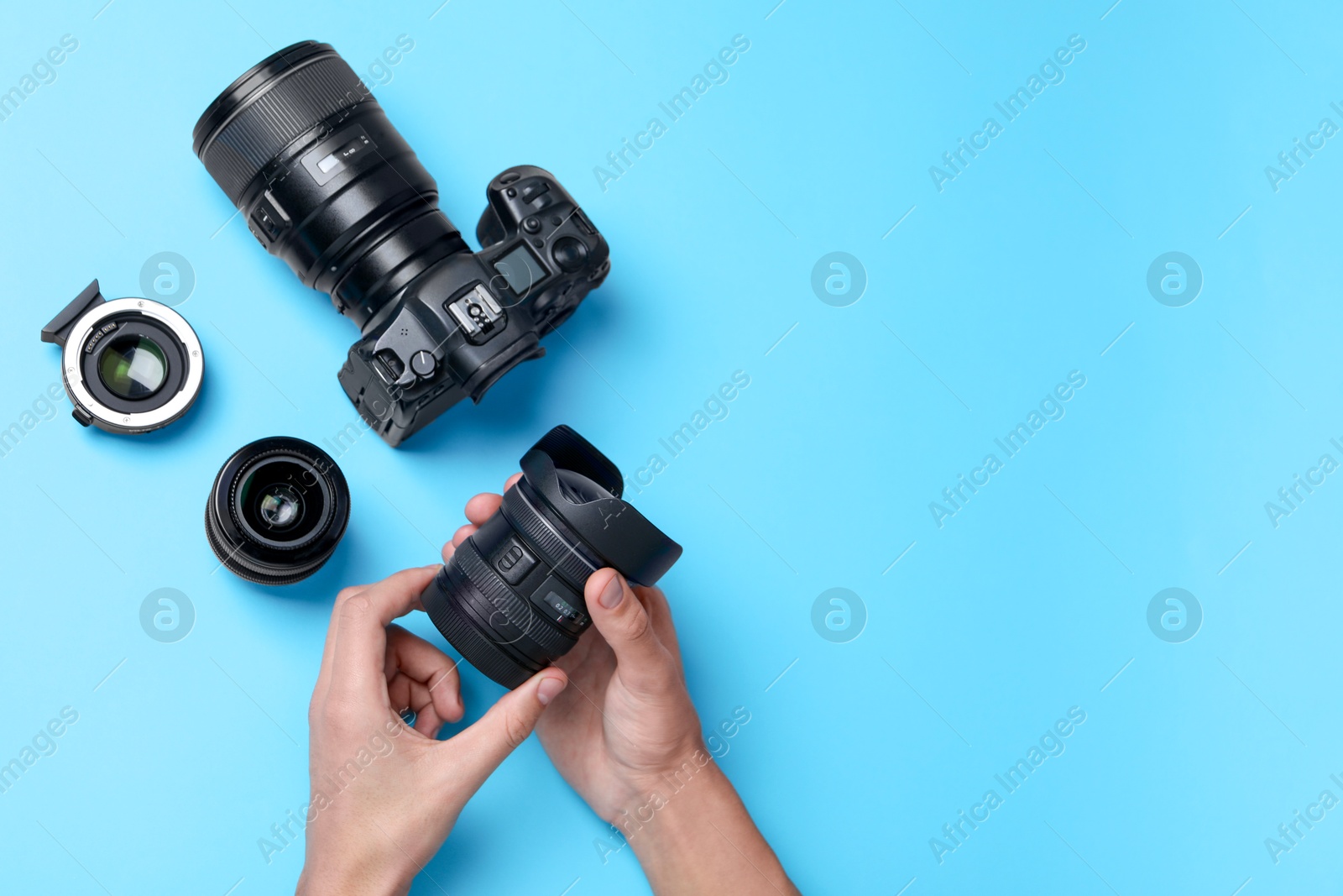 Photo of Photographer with lens and professional camera on light blue background, top view. Space for text