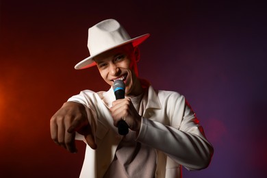 Photo of Talented singer performing on dark background with color lights