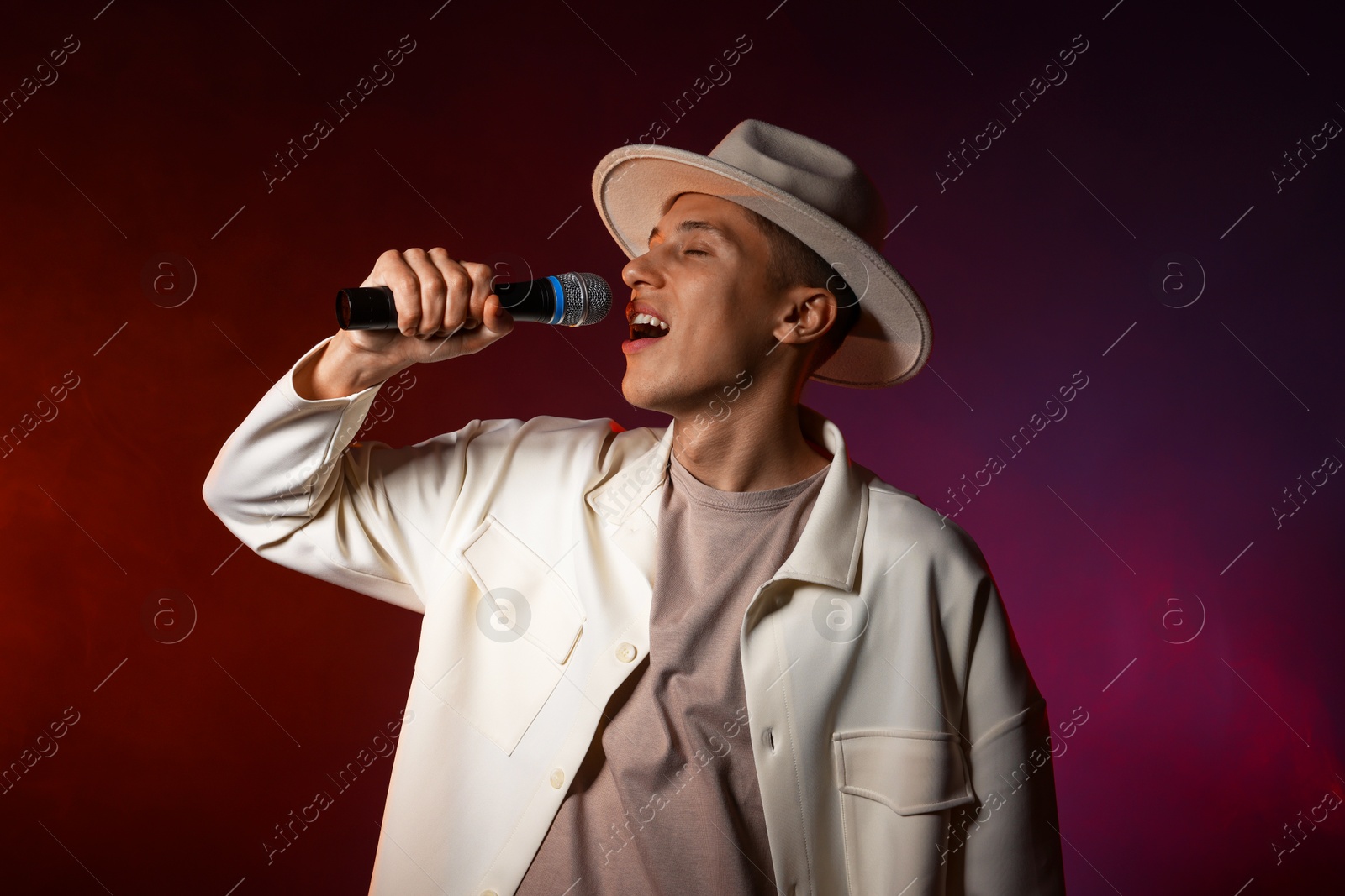 Photo of Talented singer performing on dark background with color lights