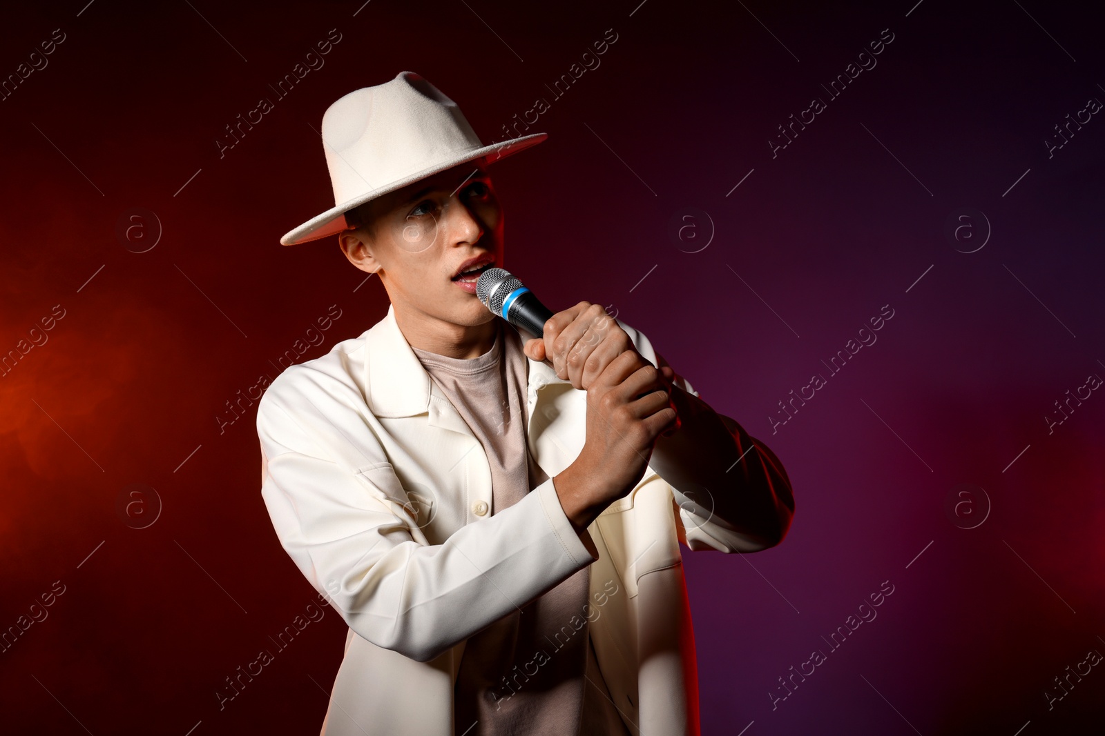 Photo of Talented singer performing on dark background with color lights. Space for text