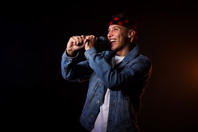 Photo of Talented singer performing on dark background with color light