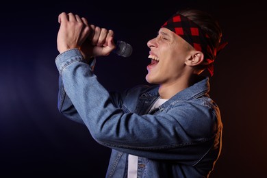 Photo of Talented singer performing on dark background with color light