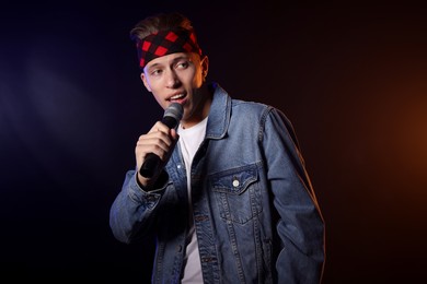 Photo of Talented singer performing on dark background with color light