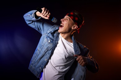 Photo of Talented singer performing on dark background with color light