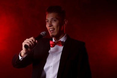 Photo of Talented singer performing on red background with smoke