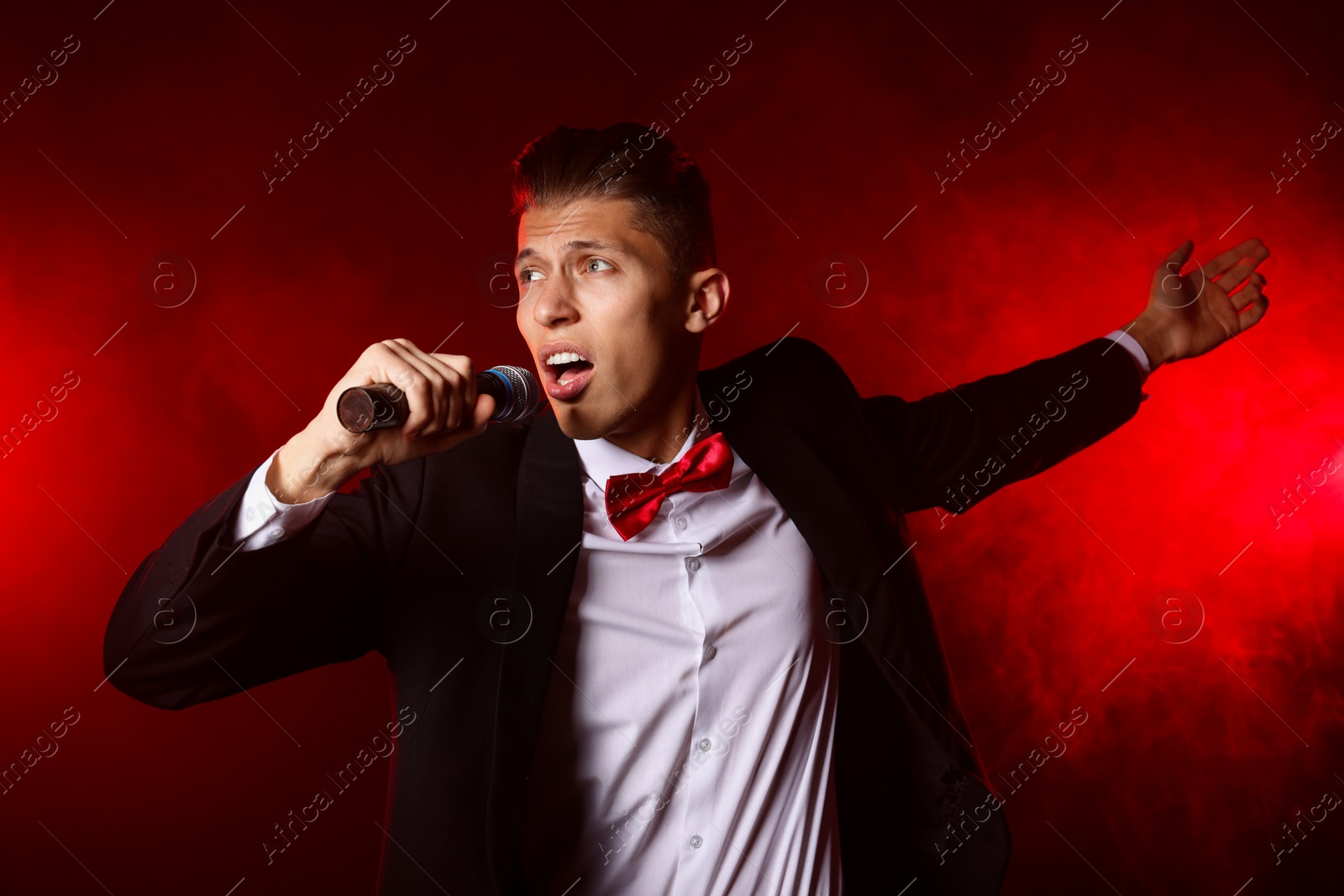 Photo of Talented singer performing on red background with smoke