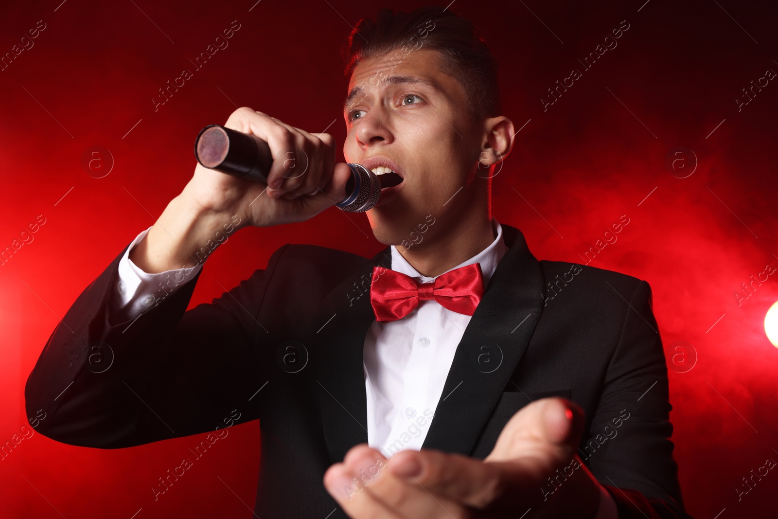 Photo of Talented singer performing on red background with smoke