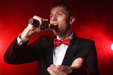 Photo of Talented singer performing on red background with smoke