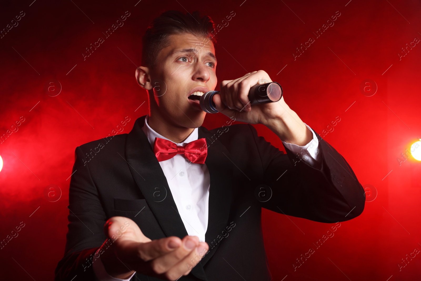 Photo of Talented singer performing on red background with smoke