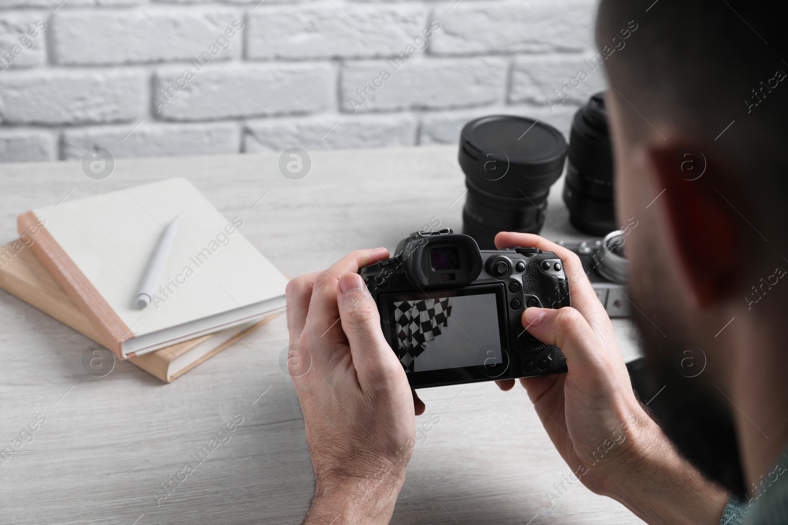 Photo of Photographer with professional camera at wooden table, selective focus