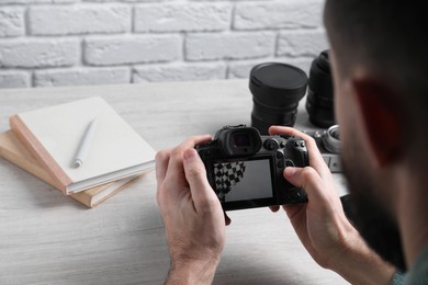 Photo of Photographer with professional camera at wooden table, selective focus