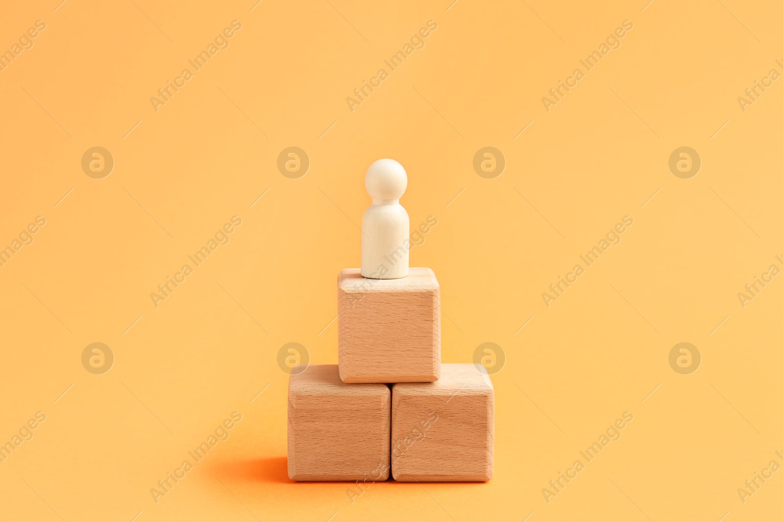 Photo of Human figure on wooden cubes against orange background. Competition concept