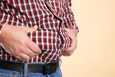 Photo of Overweight man in tight shirt on beige background, closeup. Space for text