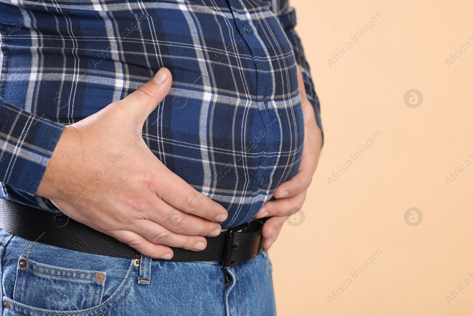 Photo of Overweight man in tight shirt on beige background, closeup. Space for text