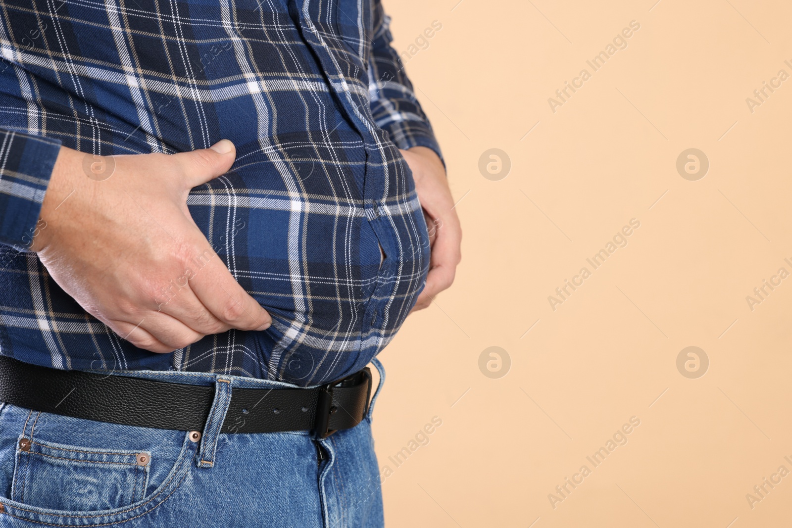 Photo of Overweight man in tight shirt on beige background, closeup. Space for text