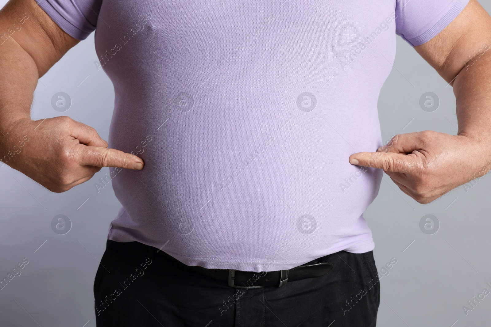 Photo of Overweight man in tight t-shirt on grey background, closeup