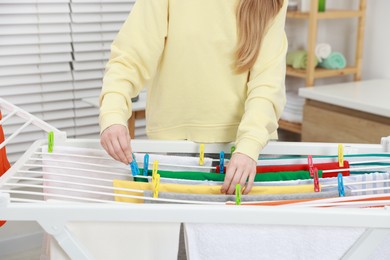 Photo of Woman hanging fresh clean laundry on drying rack at home, closeup