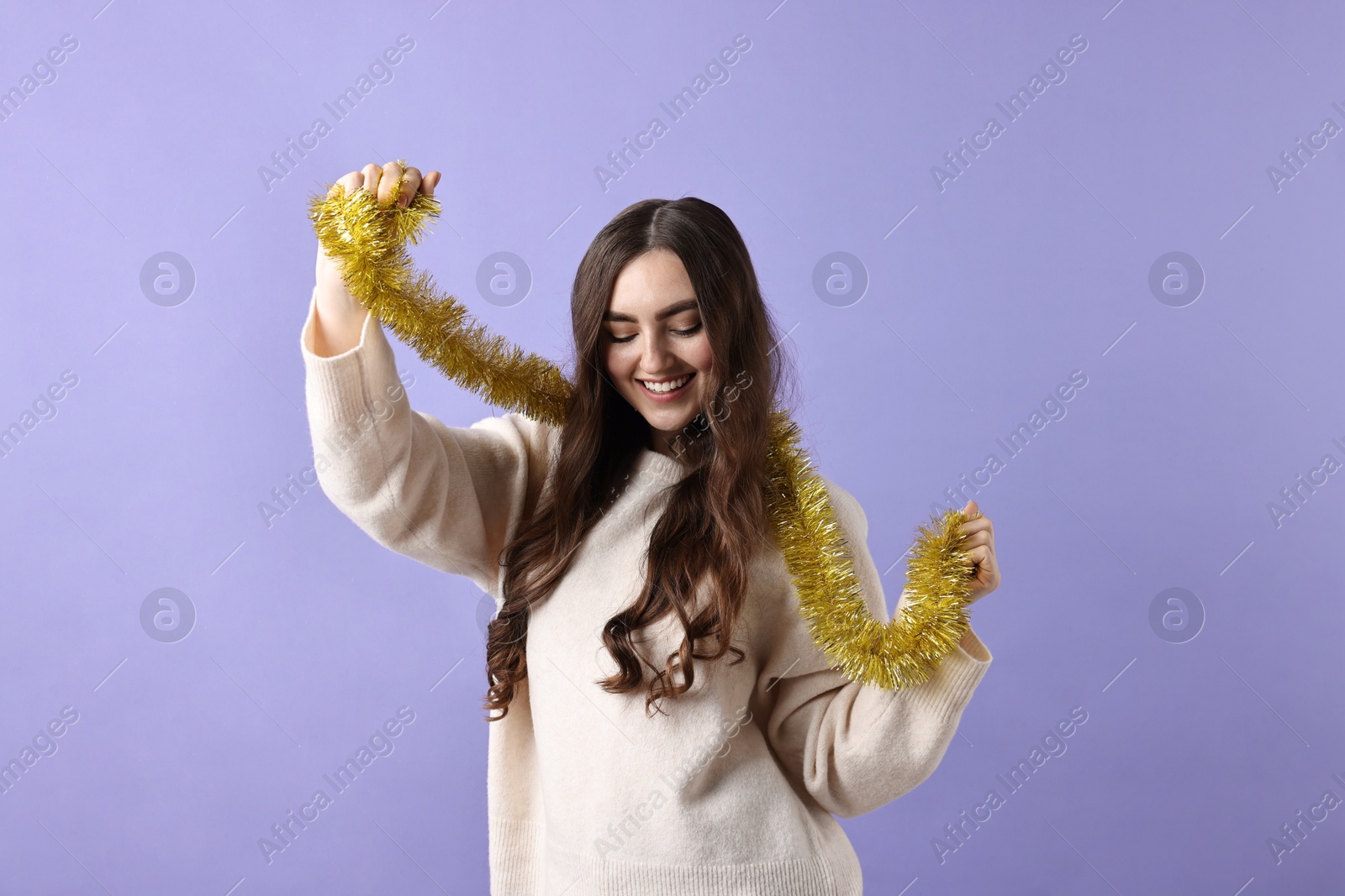 Photo of Happy young woman with tinsel on purple background