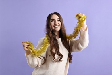 Photo of Happy young woman with tinsel on purple background