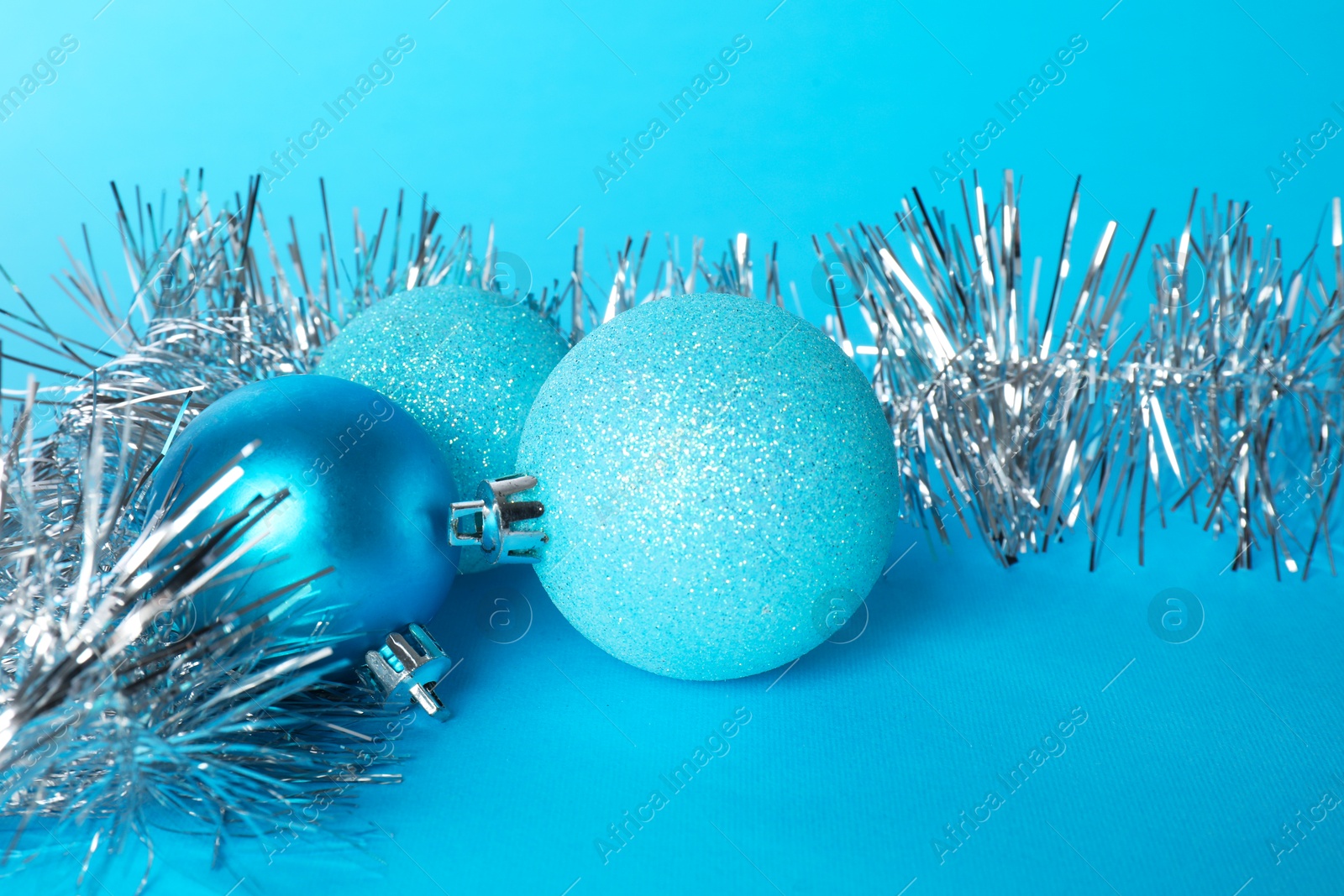 Photo of Beautiful Christmas balls and shiny tinsel on light blue background