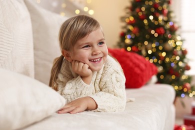 Photo of Little girl lying on sofa at home. Christmas celebration