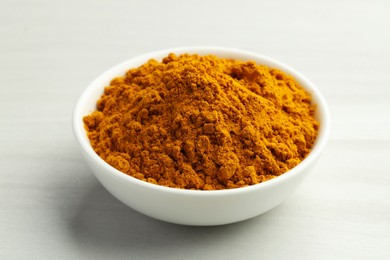 Photo of Turmeric powder in bowl on white table, closeup