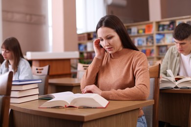 Photo of Beautiful woman with books at desk in public library