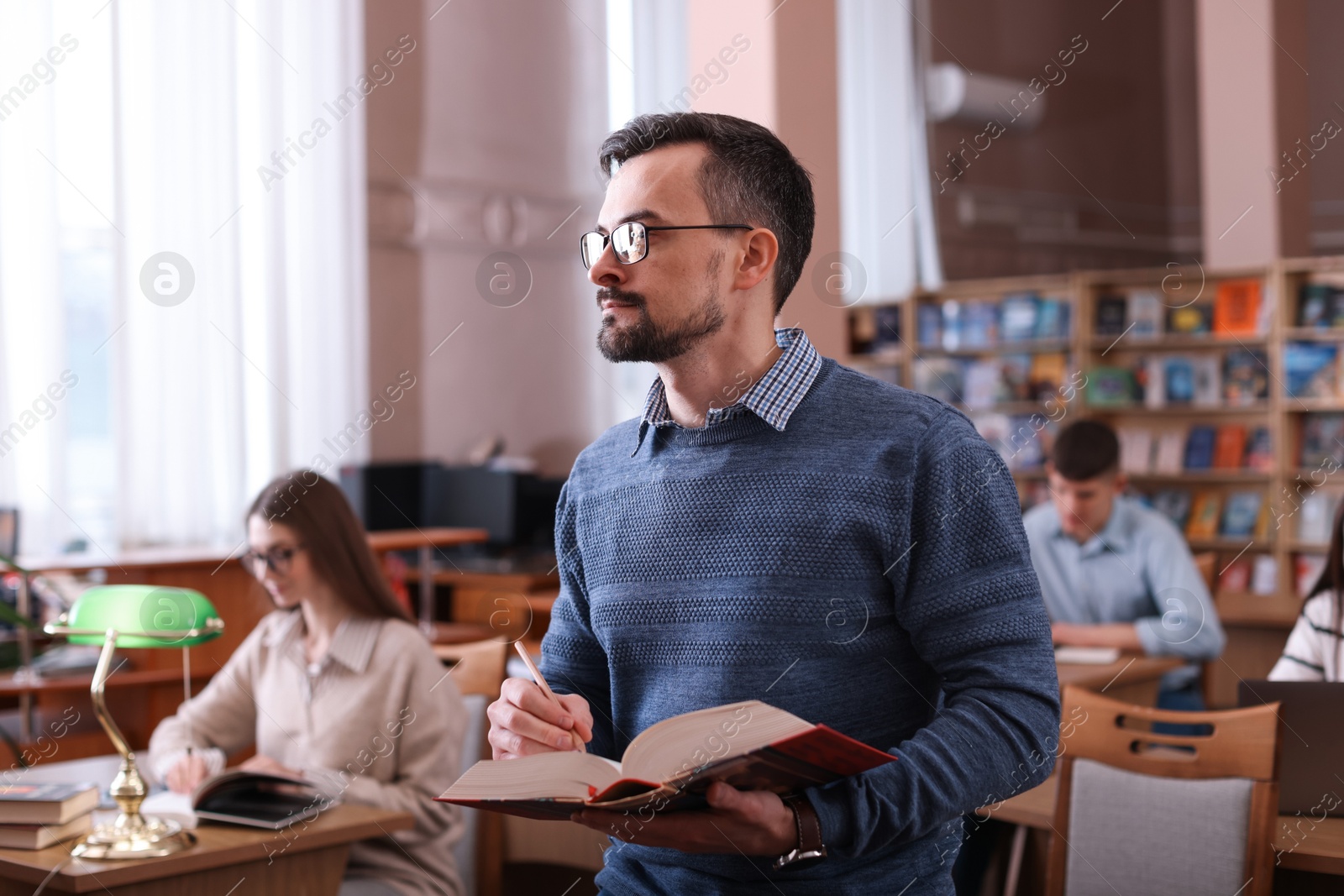 Photo of Handsome man with book in public library