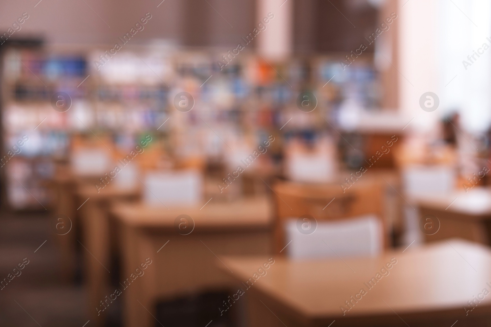 Photo of Desks and chairs in public library room, blurred view