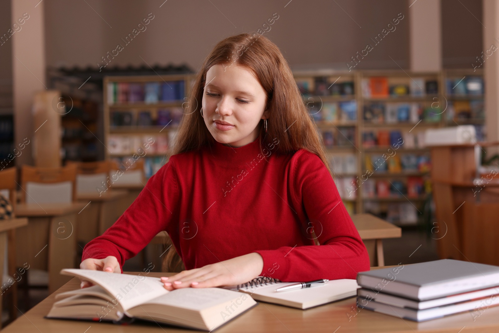 Photo of Girl reading book at desk in public library