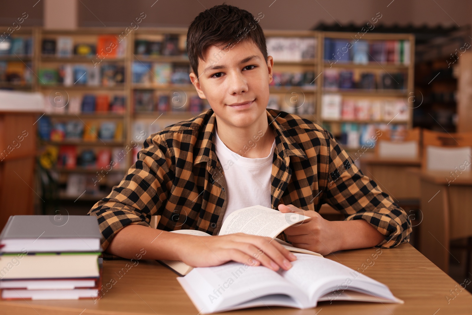 Photo of Boy studying at wooden desk in public library