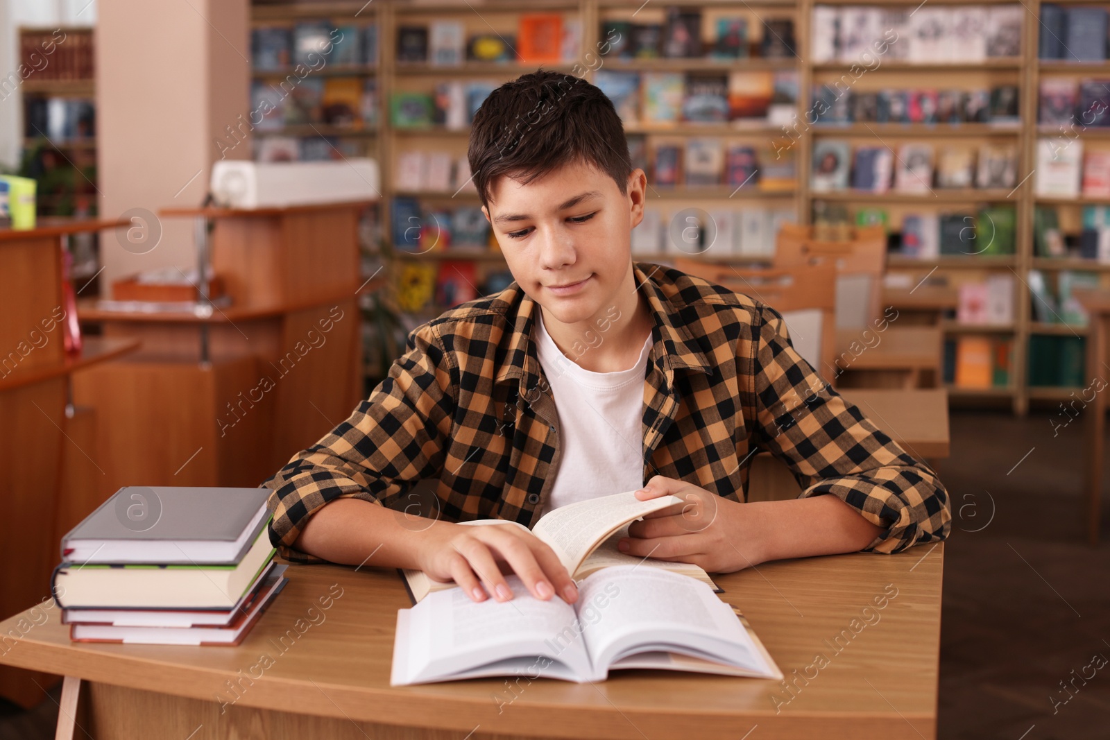 Photo of Boy studying at wooden desk in public library